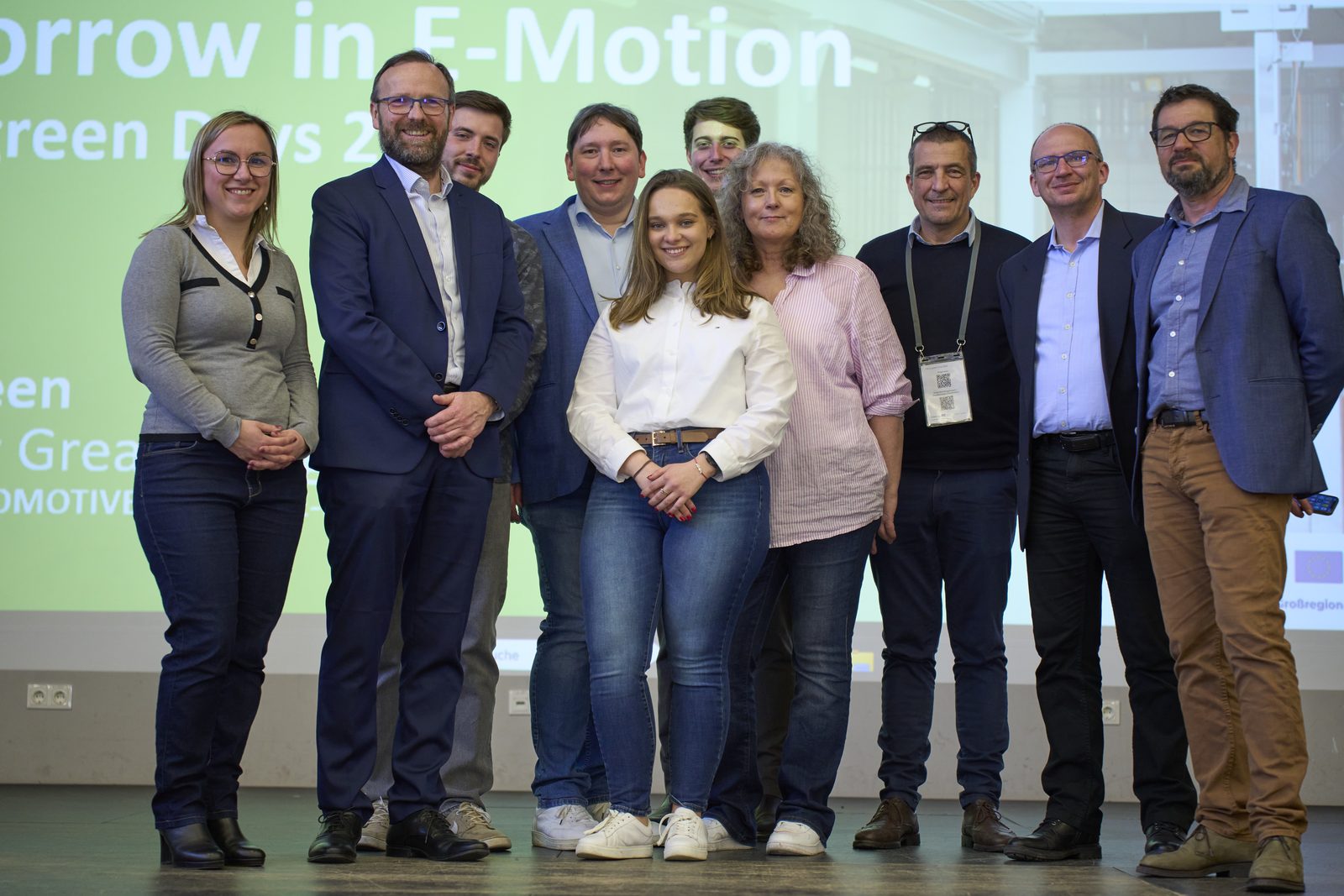 Gruppenfoto von Veranstaltern und Speakern auf der Bühne vor der Folie „Tomorrow in E-Motion“.