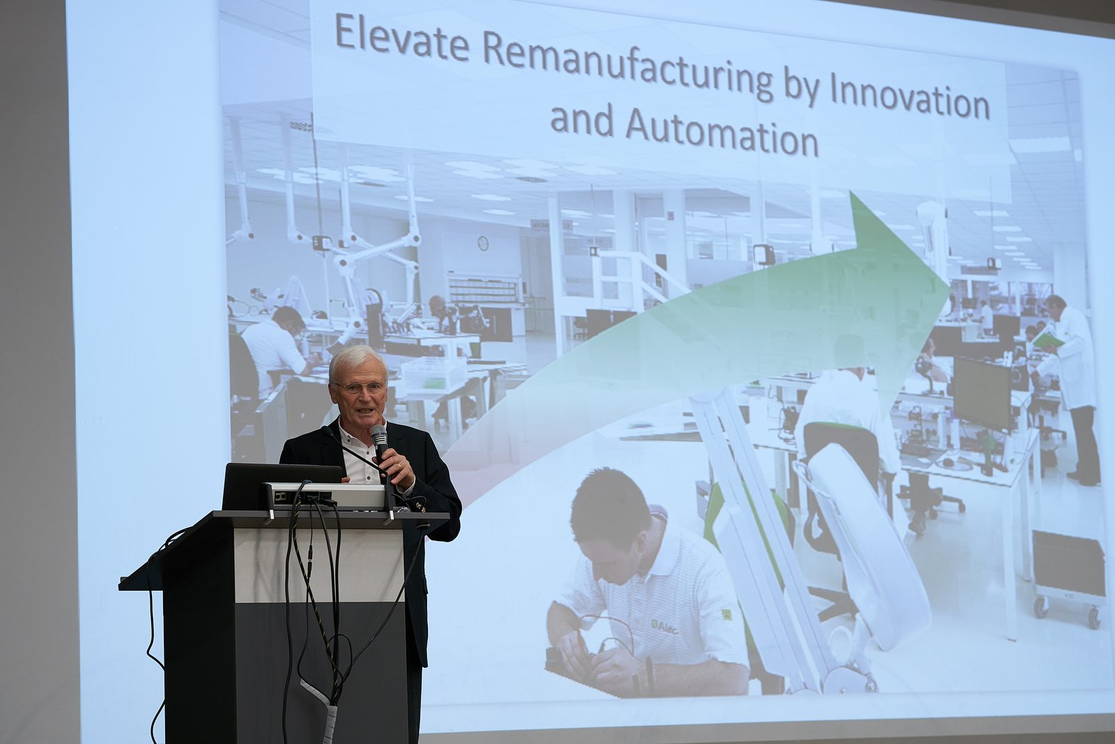 A speaker at the lectern in front of the slide 