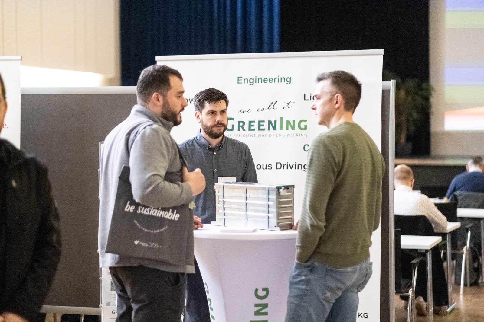 Three people talking at an exhibition stand.